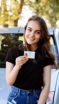 Proud young girl with car licence just after finishing driving school and getting drivers license